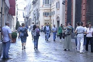 Tourists in Via Garibaldi - one taking a picture with her digicam.