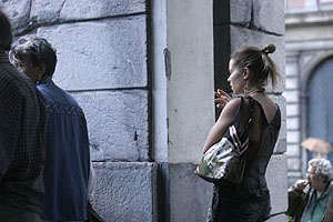 Young woman smoking while waiting for the bus near Piazza de Ferrari