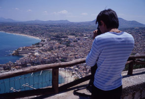 American tourist photographing a town in Sicily