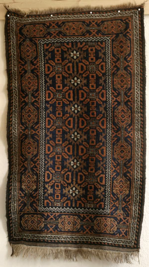 full view of baluch rug with serrated diamonds and flowers